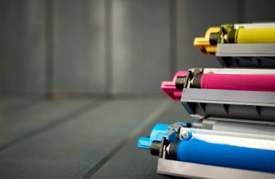 Magenta, cyan and yellow laser print ink cartridges on wood background