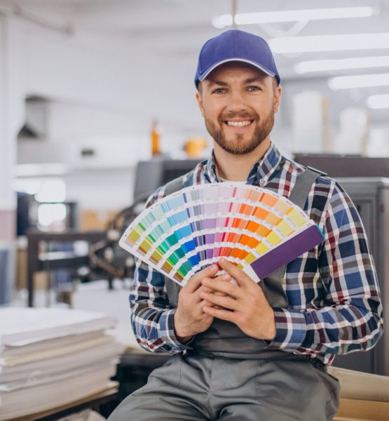 Man working in printing house with paper and paints